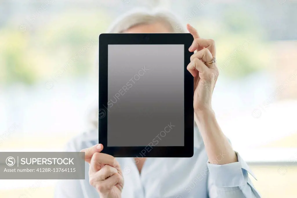 Woman holding digital tablet in front of her face.