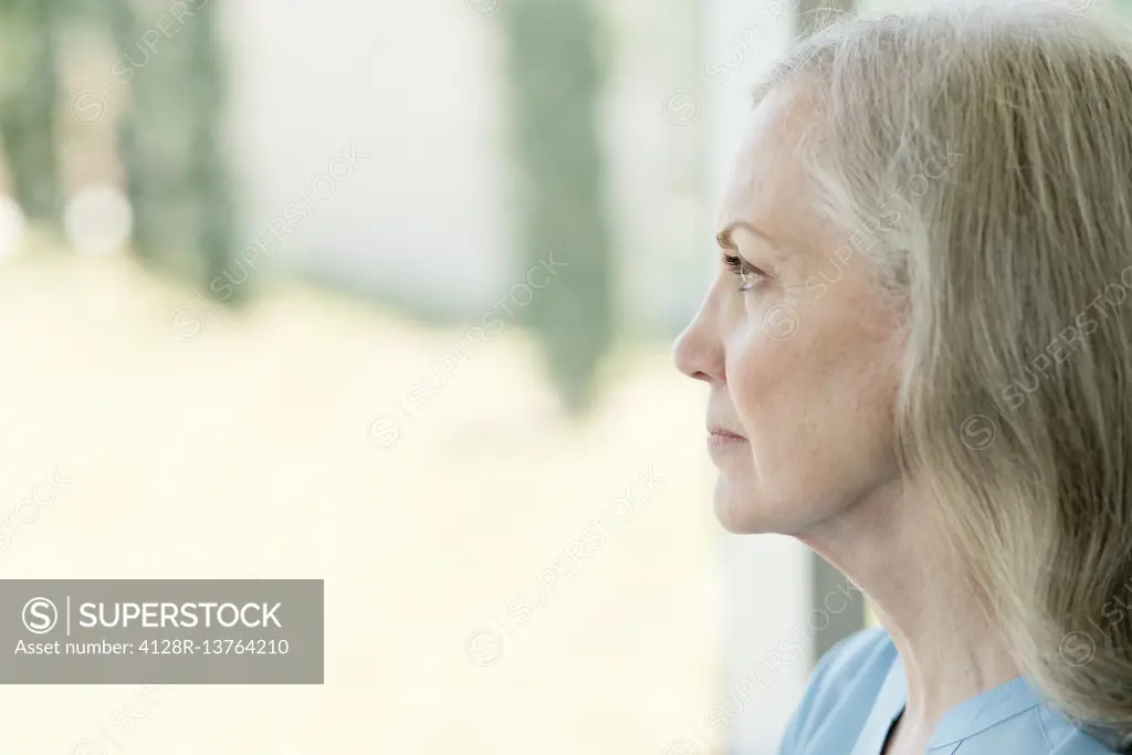 Senior woman looking through window.