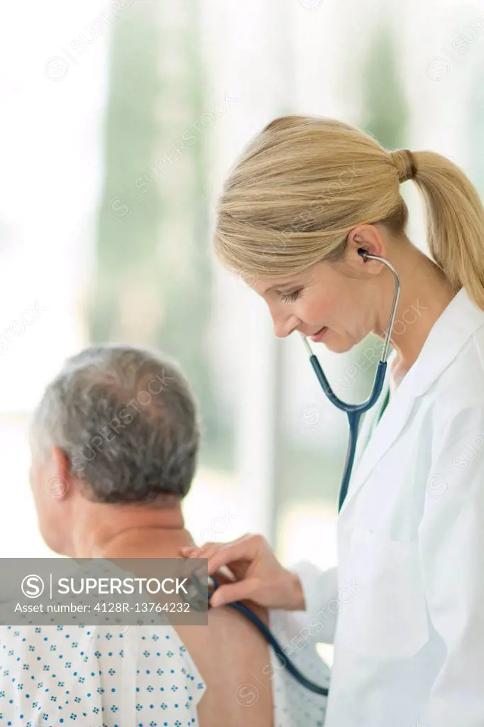 Female doctor using stethoscope on male patient.
