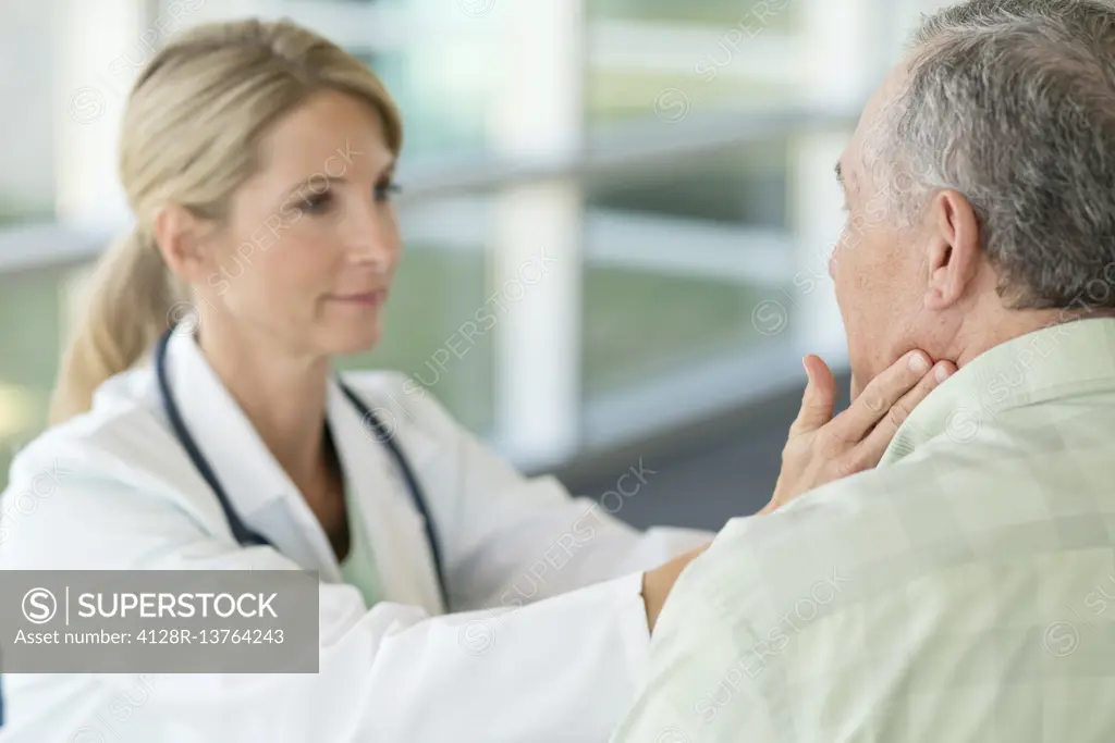 Female doctor touching senior man's neck.