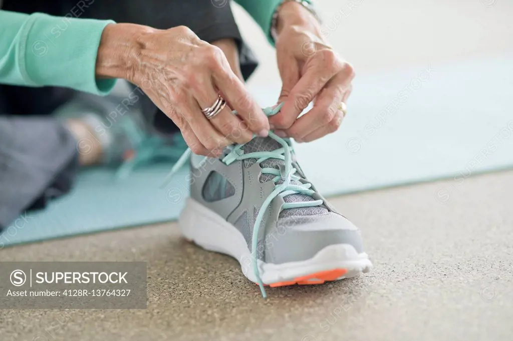 Senior woman lacing up trainers, close up.