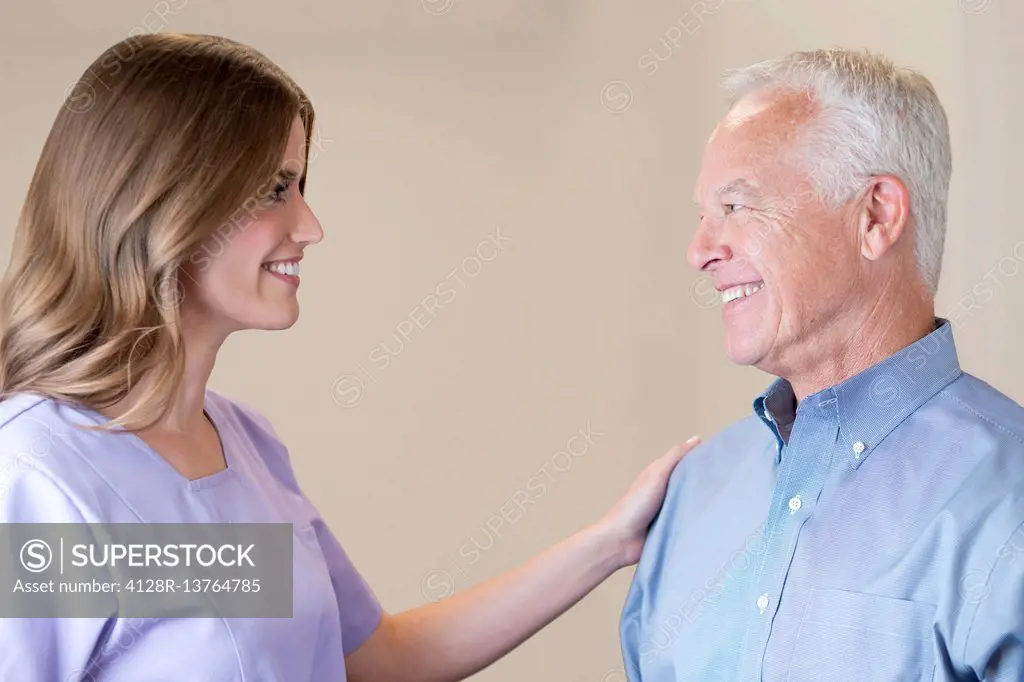 Mid adult woman with hand on senior man's shoulder.