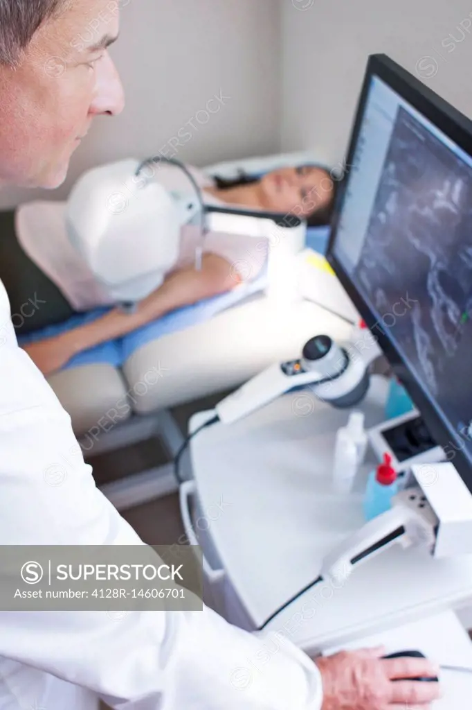Doctor looking at computer monitor, patient on bed