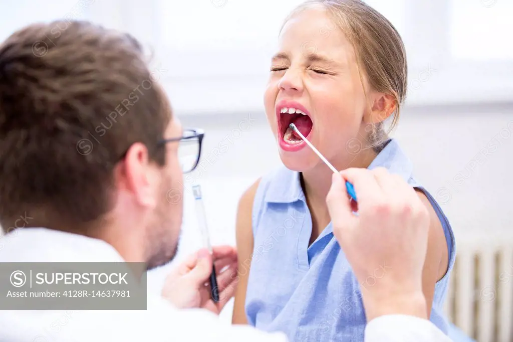Doctor taking a swab from a girl's mouth