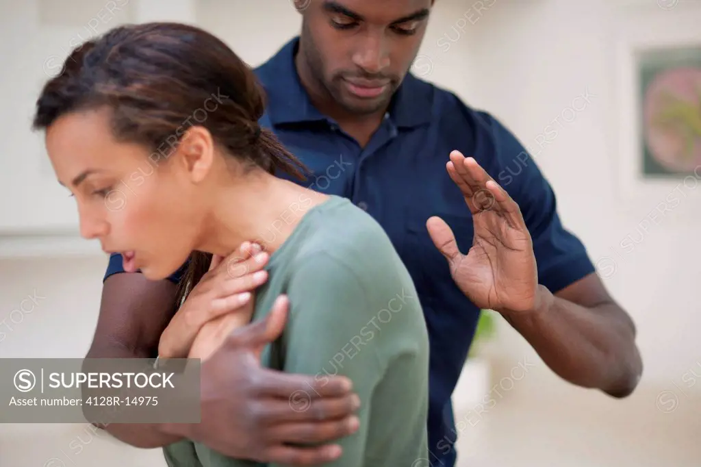 Woman choking. The man is trying to dislodge the foreign object by hitting her between the shoulder blades.