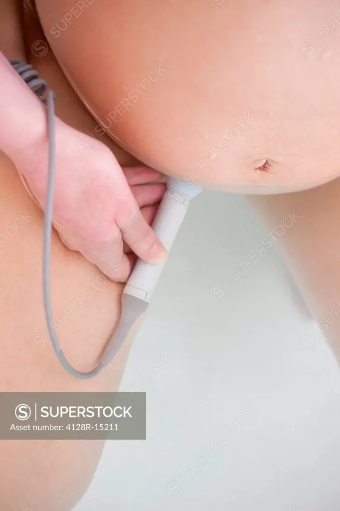Water birth. Close_up of a midwife using a doppler monitor to listen to a foetus´ heartbeat in a birthing pool.