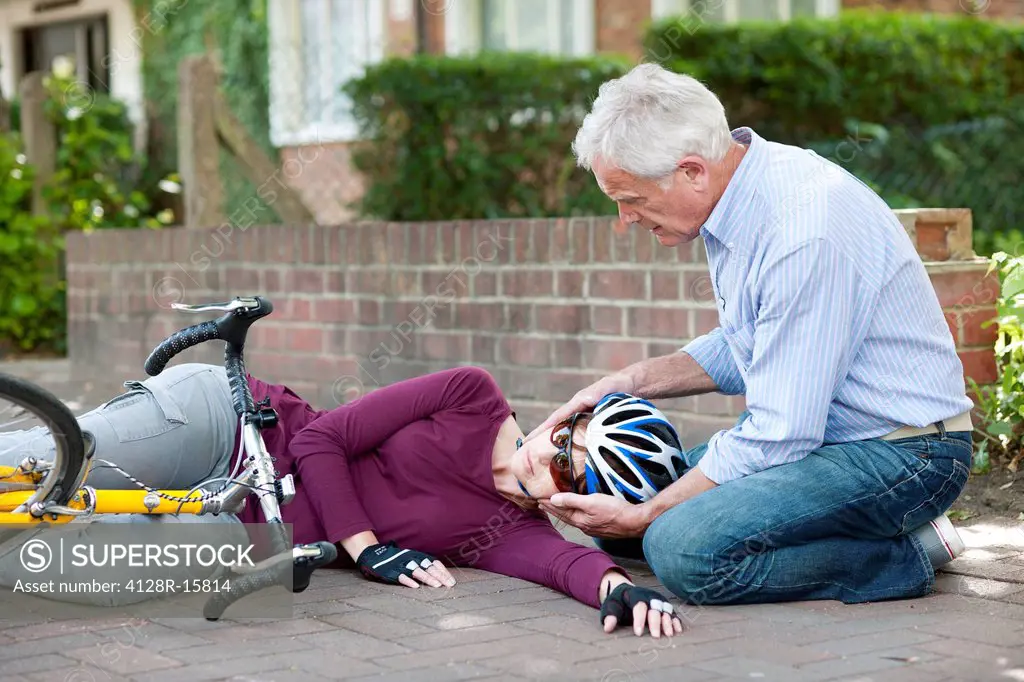 Cycling accident. Man helping a cyclist that has fallen from her bike.