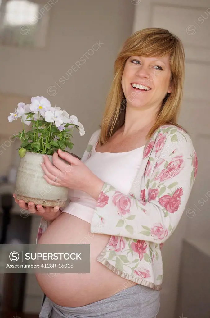 Pregnant woman with a potted plant. She is 35 weeks pregnant.