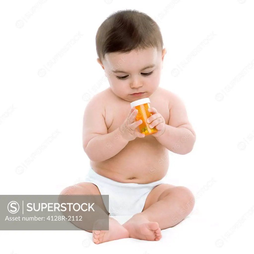 Child danger. Baby boy playing with a bottle of pills.