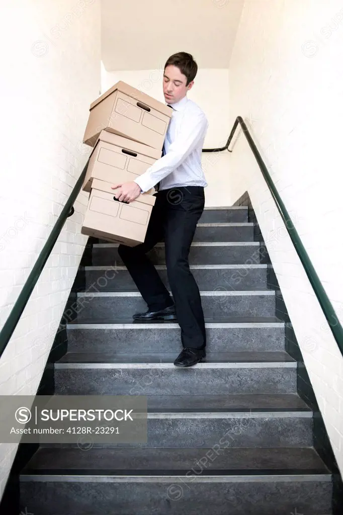 MODEL RELEASED. Carrying boxes. Office worker carrying boxes down stairs.