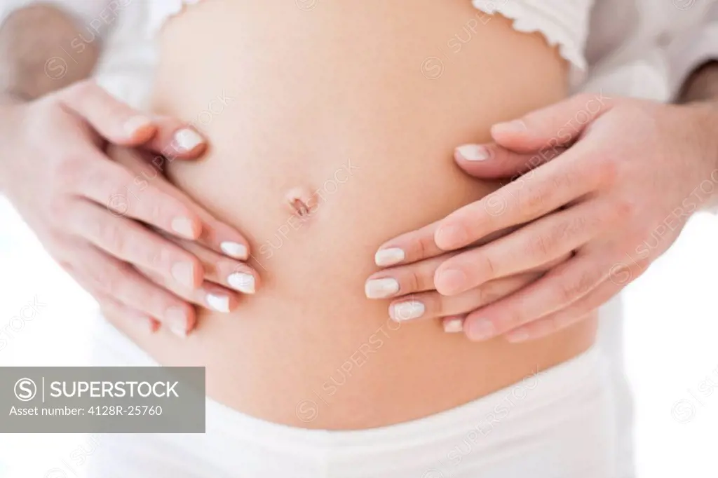 MODEL RELEASED. Couple holding pregnant woman's abdomen.