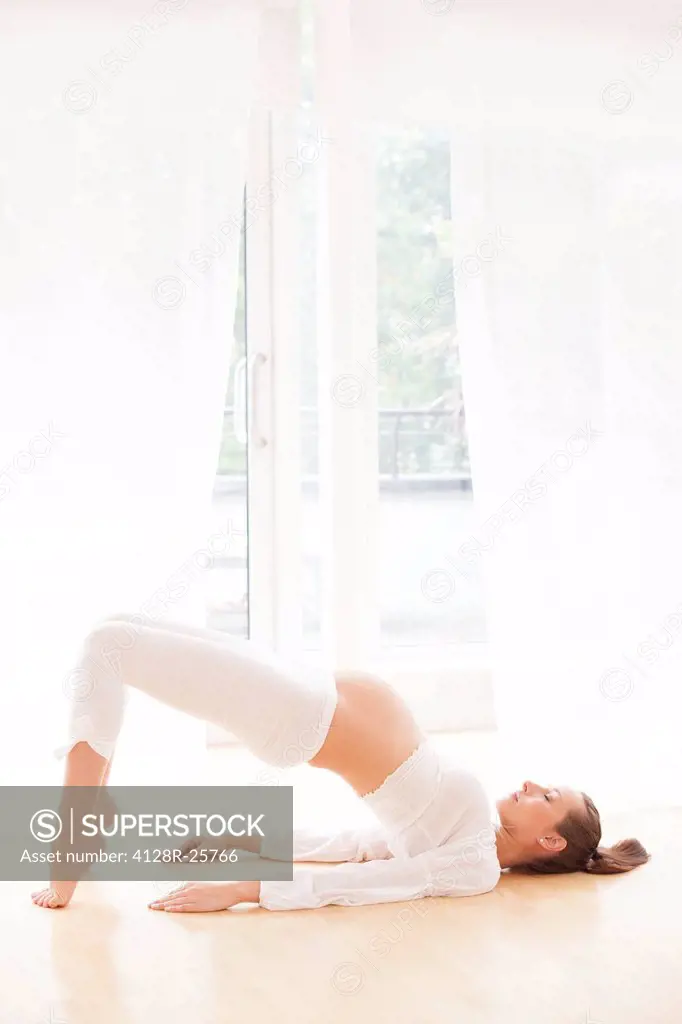 MODEL RELEASED. Pregnant woman practicing yoga.