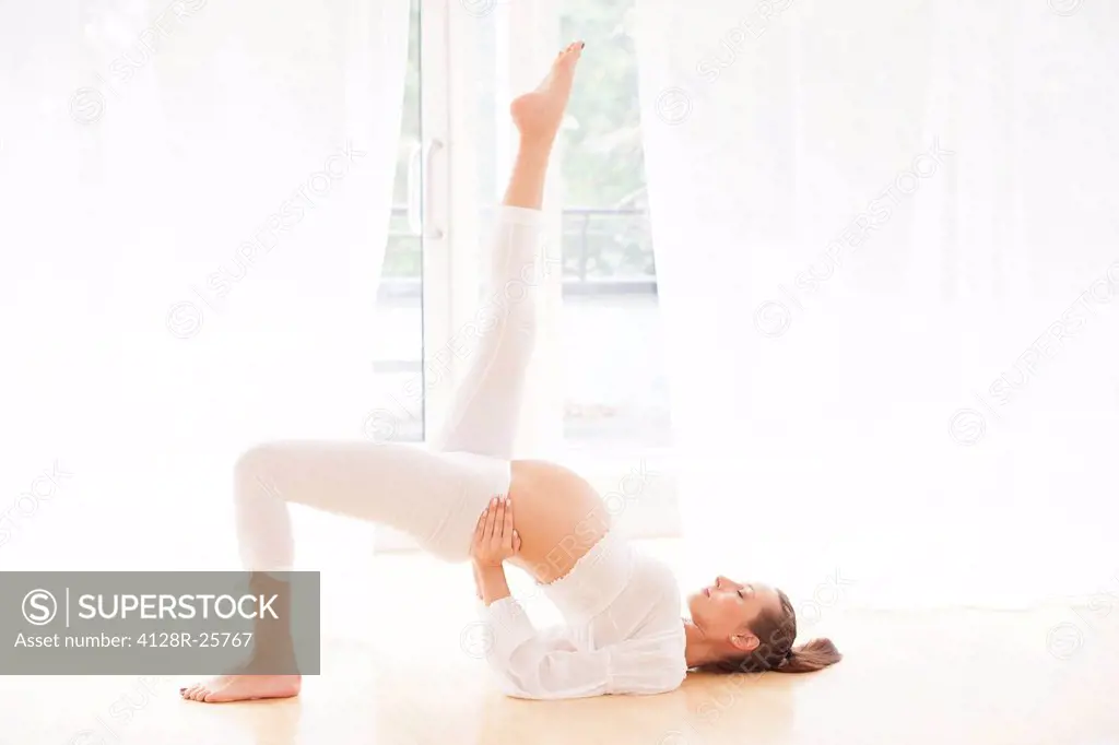 MODEL RELEASED. Pregnant woman practicing yoga.