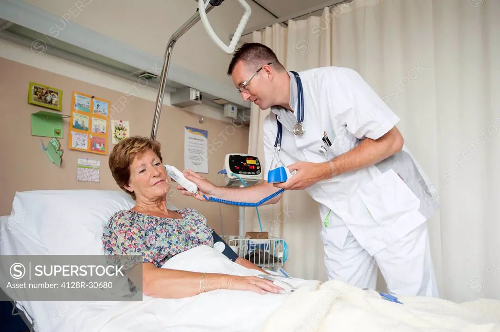 MODEL RELEASED. Taking temperature. Nurse taking a patients temperature with a digital thermometer.