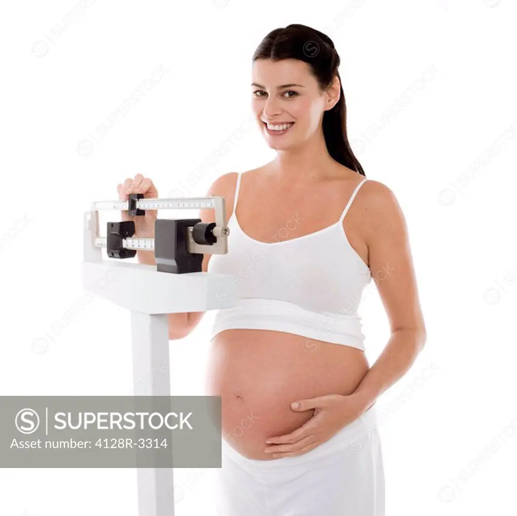 Pregnant woman weighing herself. She is 27 weeks pregnant.