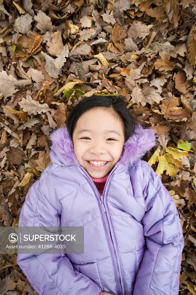 Smiling girl lying on autumn leaves