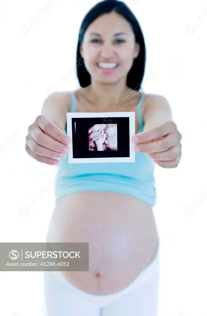 Pregnant woman holding her 3D baby scan printout. She is eight months pregnant.
