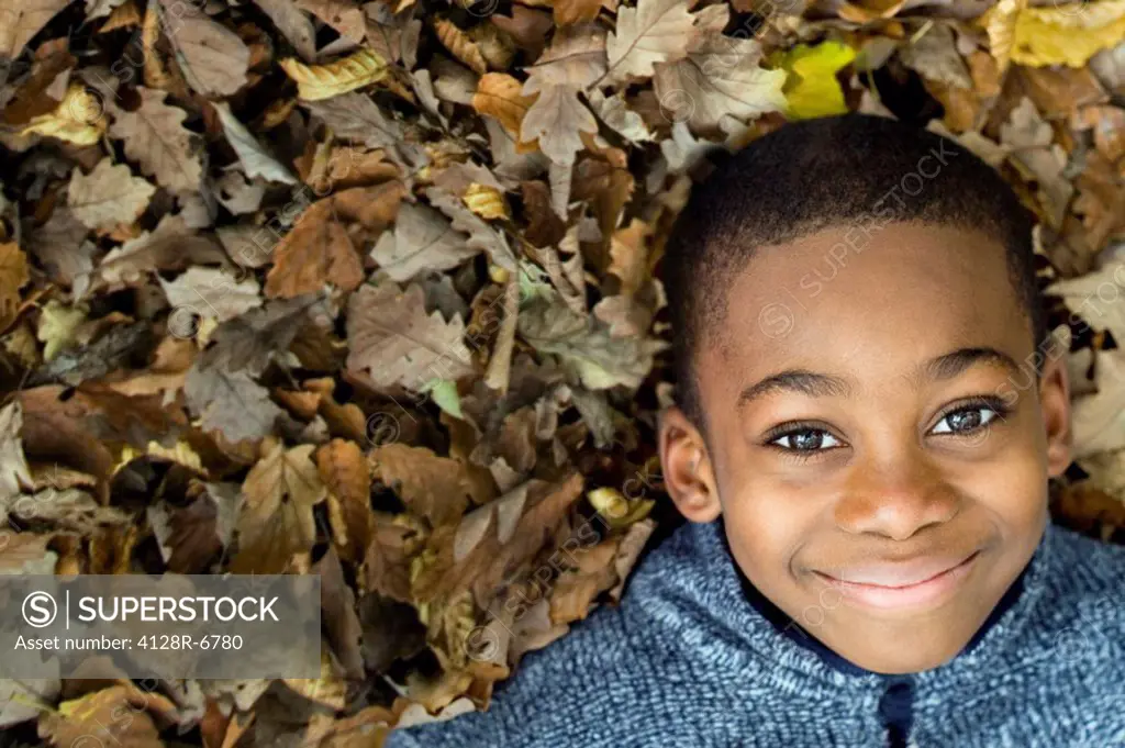 Smiling boy lying on autumn leaves
