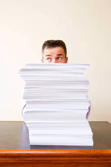 Businessman behind stack of papers
