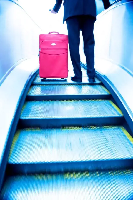 Businessman travelling up an escalator