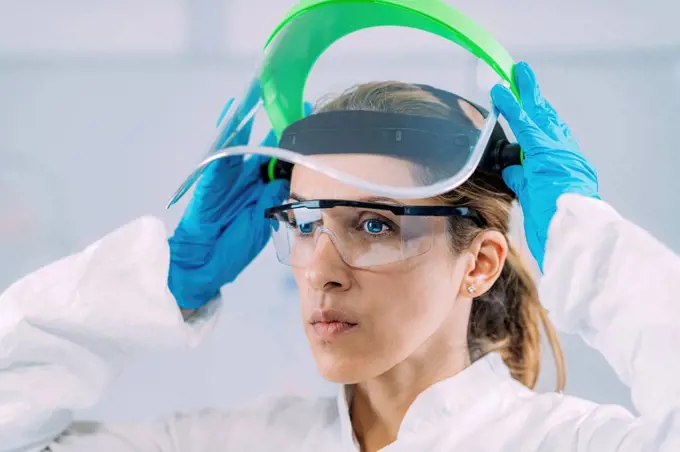 Lab technician putting protective face shield on