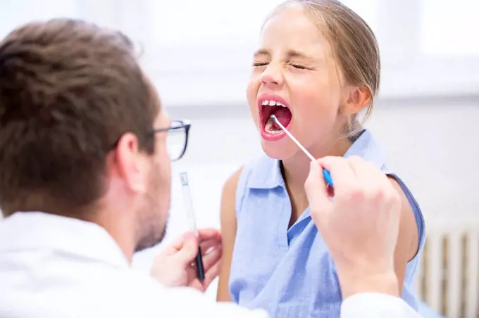 Doctor taking a swab from a girl's mouth