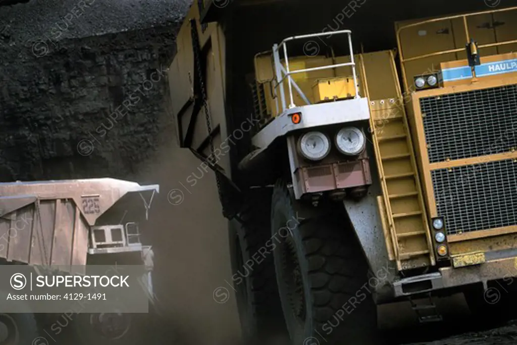 Close-up of two dump trucks in coal mine
