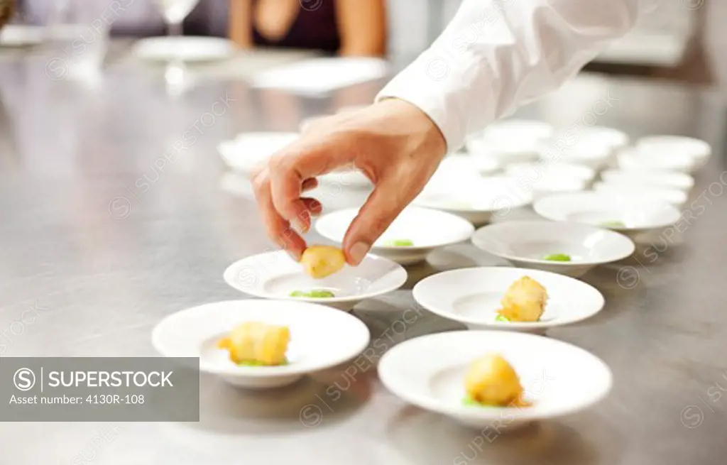 USA, New York City, Brooklyn, close up of chef's hand putting appetizers on plates