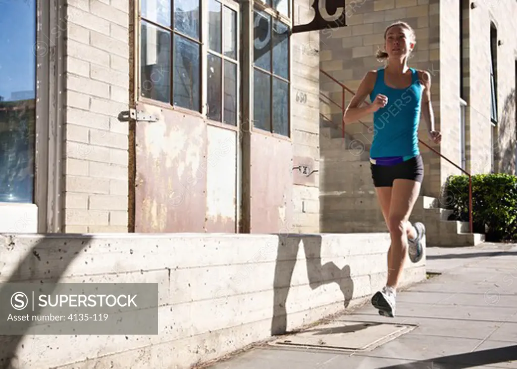 Female athlete running on sidewalk, Midtown, San Diego, California, USA