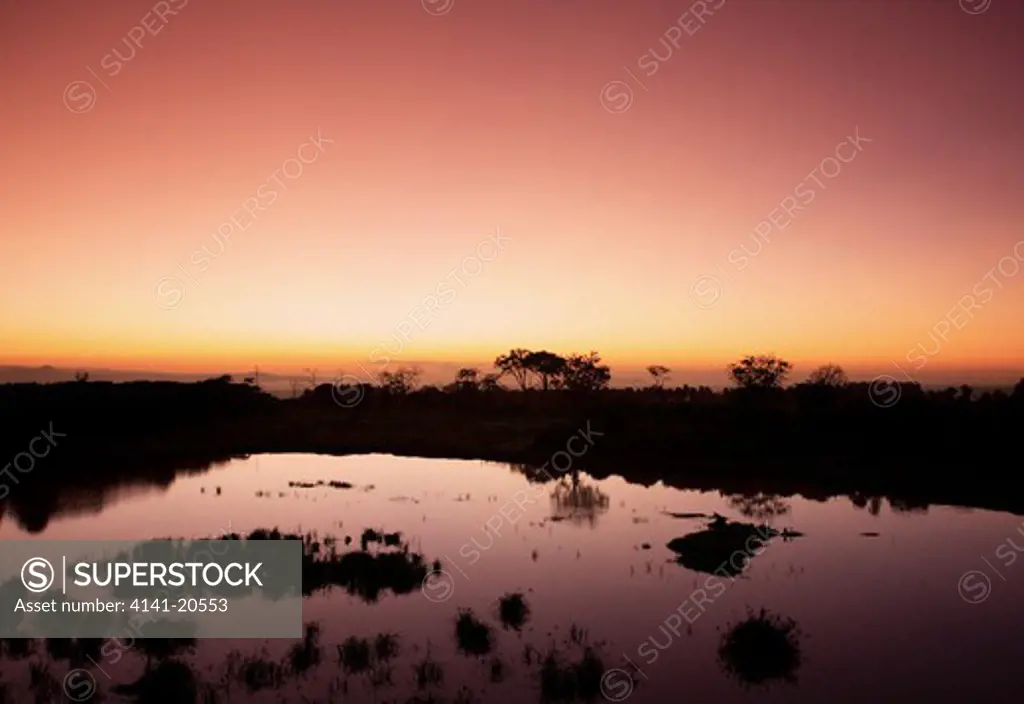 early morning kenyan sunrise over a waterhole 