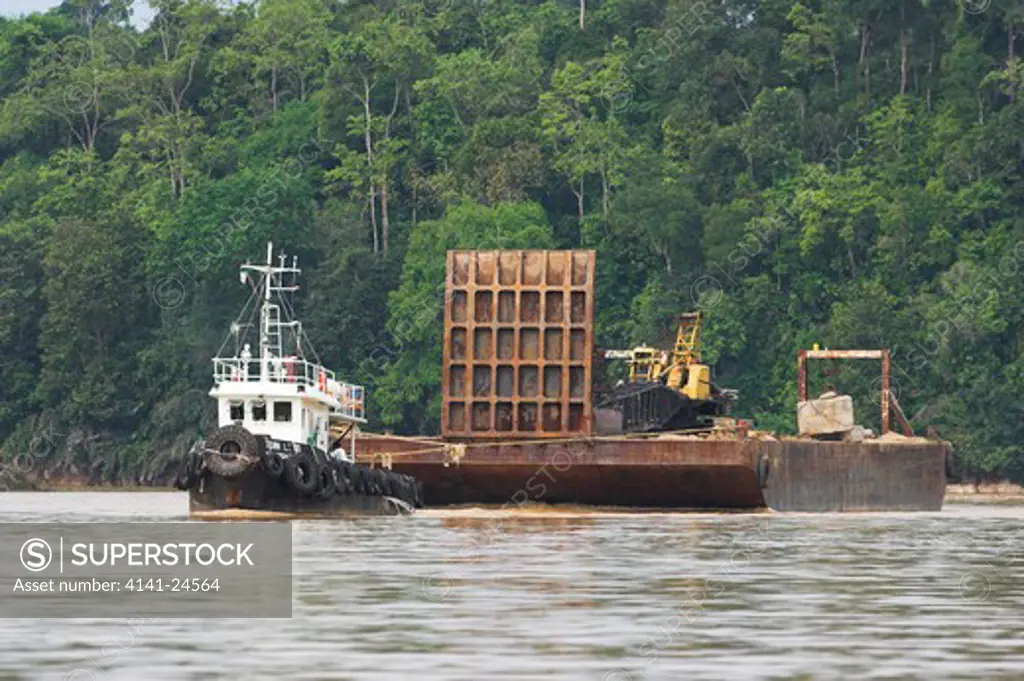 heavy machinery being moved by boat in the timber/oil palm industry. kinabatangan river sabah borneo.