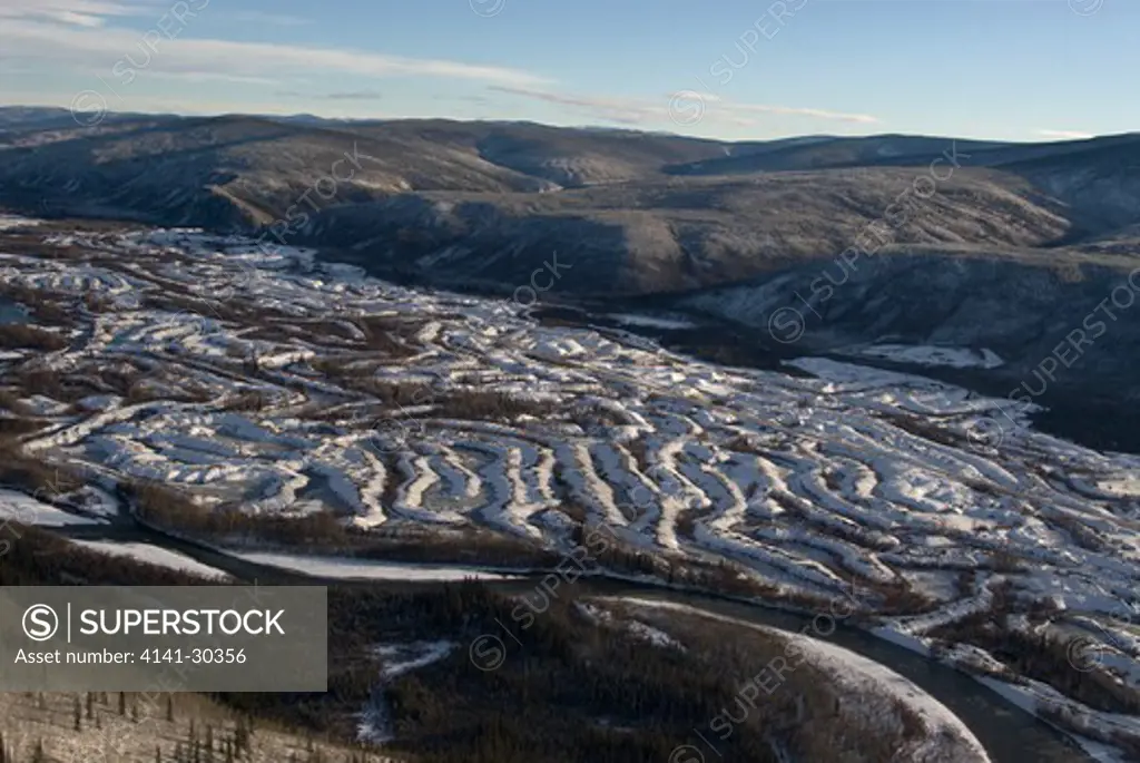aerial of gold mining dredge tailings in dawson city, yukon territory, canada. snake-shaped tailing piles were formed by a gold dredge machine working along waterway digging for gold and leaving behind tailings.