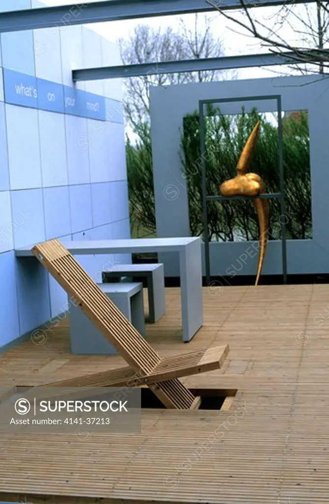 chair in decking with walls & contemporary sculpture. photographed at floriade, holland (netherlands). contemporary garden designed by buro landvast - 'whats on your mind'. 
