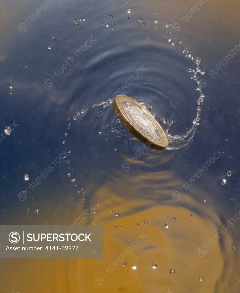 two pound coin spinning on water surface 