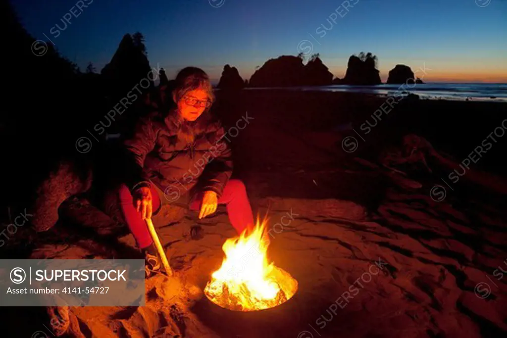 Karen Rentz In Glow Of Shi Shi Beach Campfire With Point Of Arches With Sunset Glow In The Distance, Olympic National Park, Washington State, Usa, June, Point_Of_Arches-342