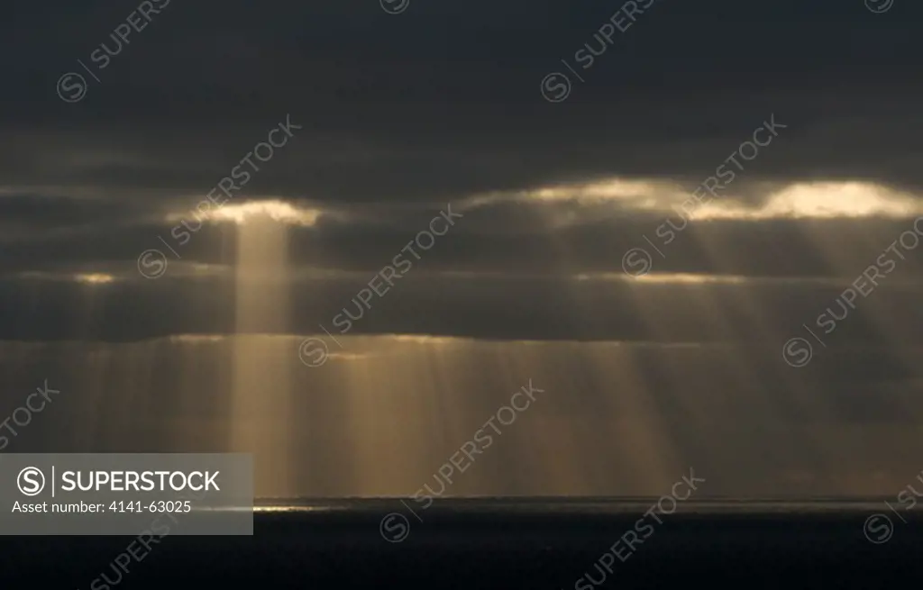 Shafts Of Evening Light Stream Through Broken Cloud.  Shetland Islands, Scotland, Uk