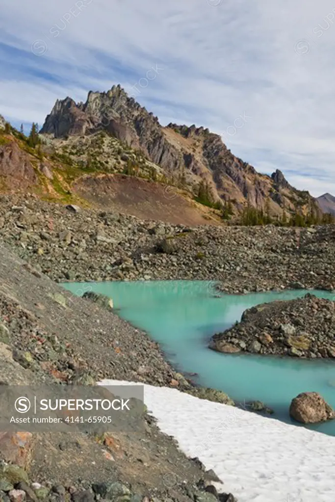 Tarn colored aqua by glacial flour in the cirque of Royal Basin, looking toward Mt. Clark and The Needles, in Olympic National Park, Washington State, USA.