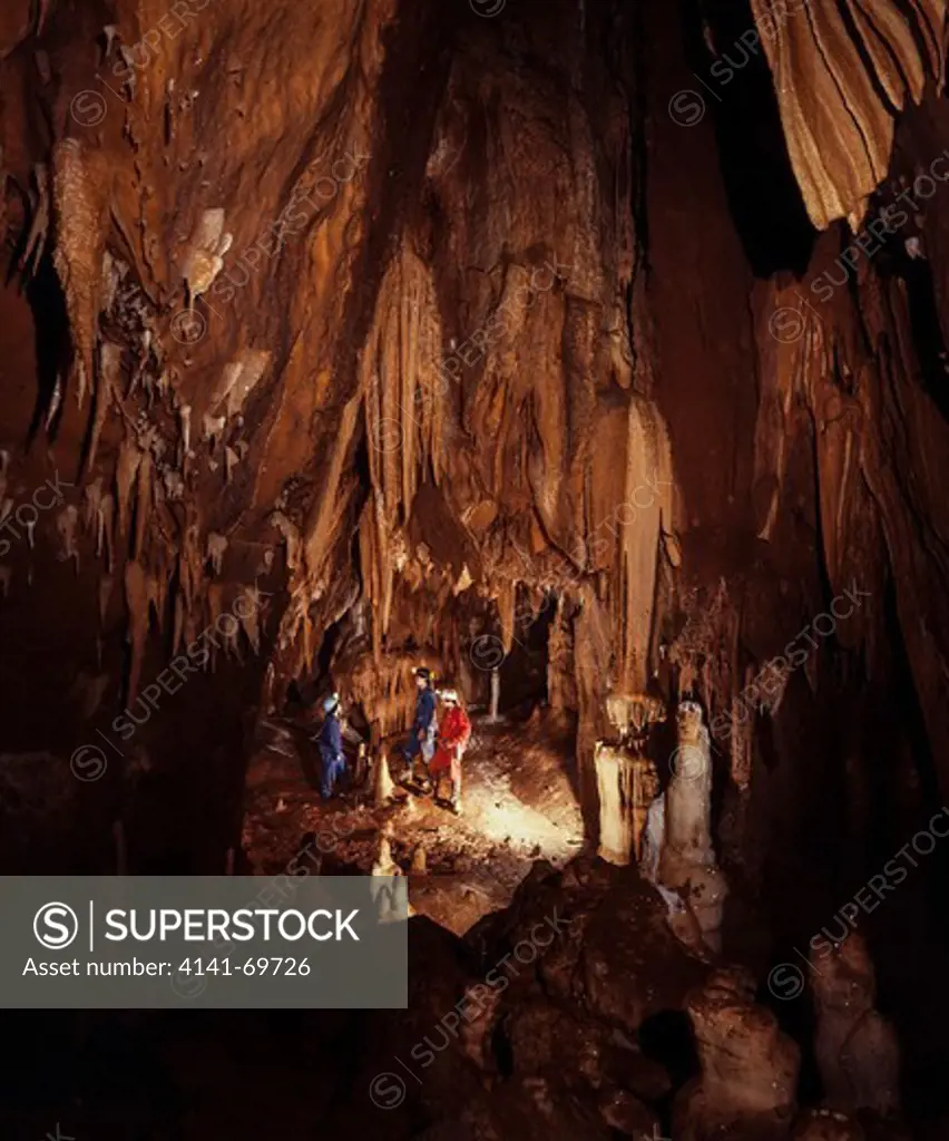 Speleologists exploring a large cave with stalactites, stalagmites, rock columns and rock curtains. Almonda cave. Central Portugal
