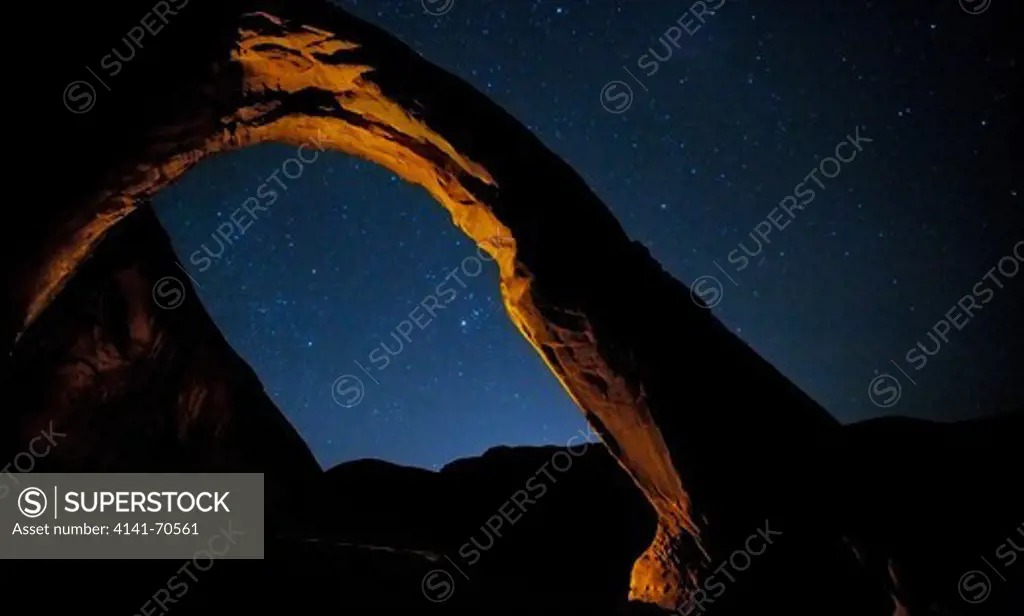 Corona Arch lightpainted after sunset against a starry sky