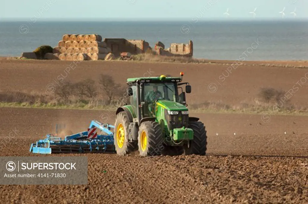 Seed drilling at Cley Norfolk in Spring and off shore windfarm