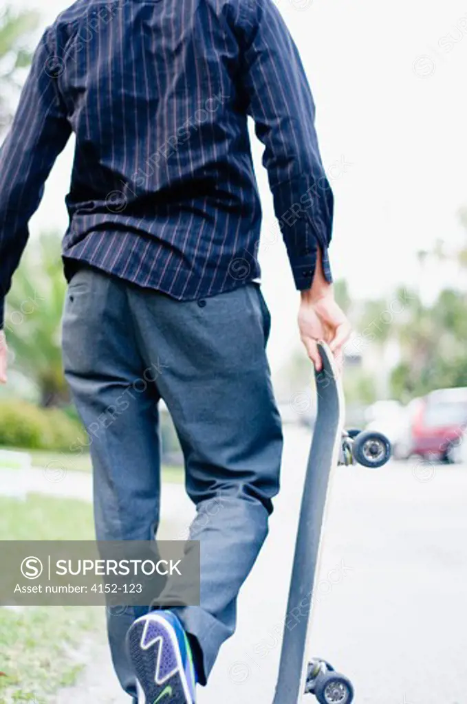 Rear view of a man holding a skateboard