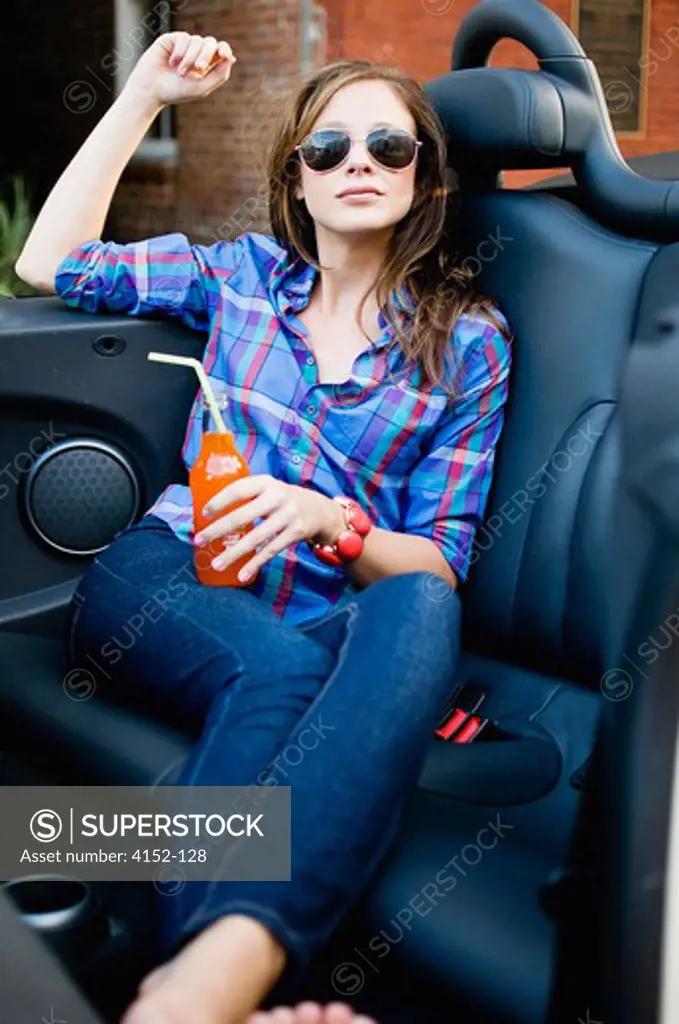 Woman holding a soft drink bottle in a car
