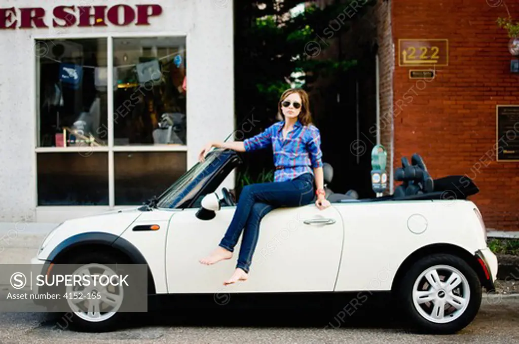 Woman sitting on a car in front of a store