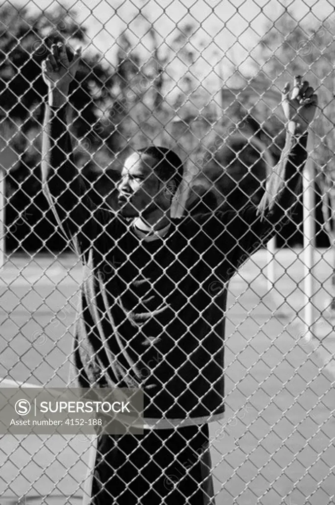 Basketball player holding chainlink fence