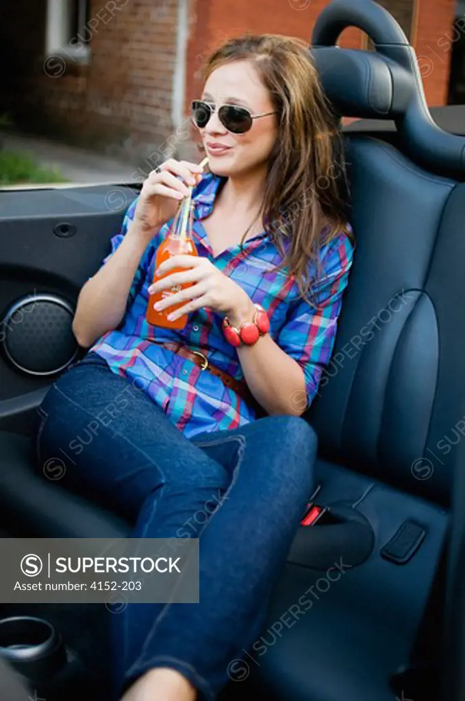 Woman drinking soft drink in a car