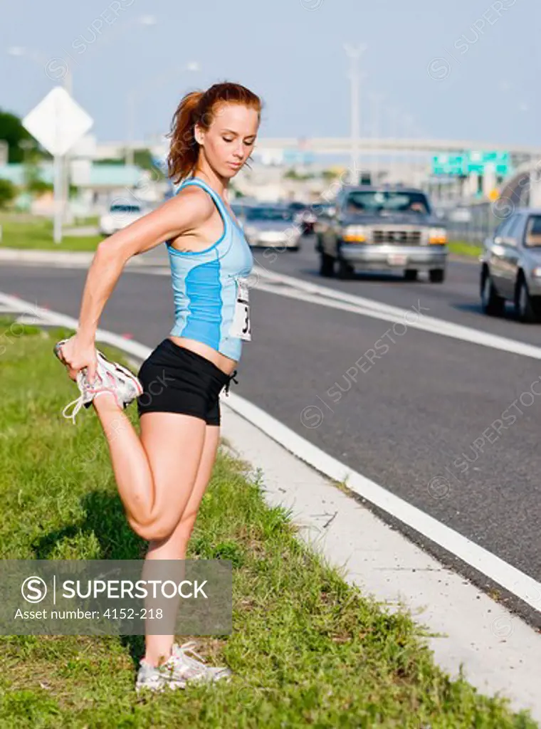 Female Athlete stretching at roadside