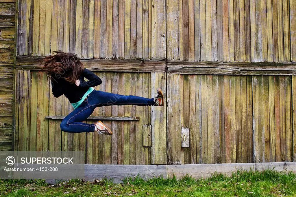 Young woman jumping and kicking in air