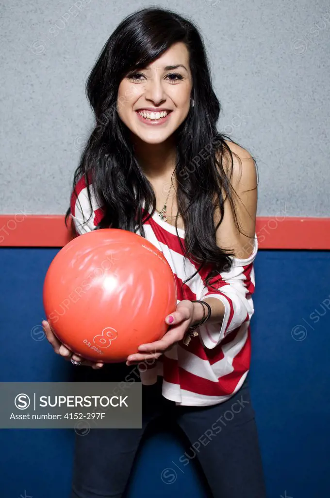 Young woman holding a bowling ball and smiling