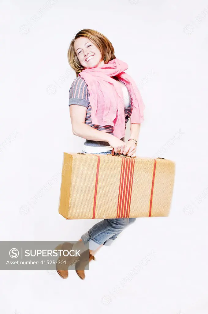 Young woman with suitcase jumping