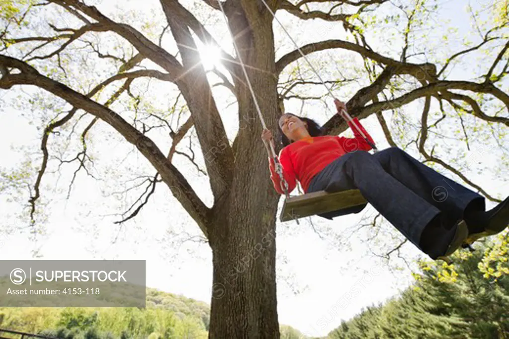 Mature woman swinging on tree swing